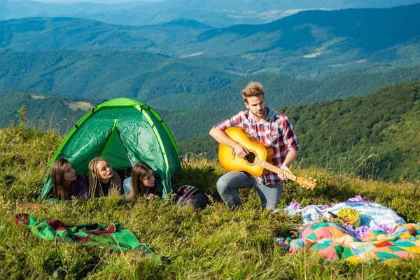 Acampar juntos es divertido, amistad picnic romántico en el campamento de turismo, canciones fogata. Grupo de jóvenes pasan tiempo libre juntos, hombres felices con la guitarra y las niñas en el camping. Jóvenes de viaje. — Foto de Stock