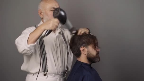 Haarfärbung bei Männern. Kerl mit gefärbten Haaren im Friseursalon. Hipster bärtige Männer färben seine Haarfarbe auf grauem Hintergrund. — Stockvideo