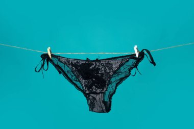 Siyah külotlu çorap. Seksi iç çamaşırları. Dantelli iç çamaşırı. Kadınlar siyah erotik külotlar. Mavi arka planda asılı kadın külotu.