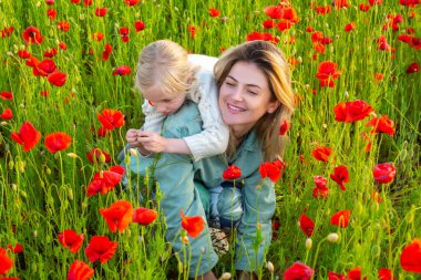 Kırmızı haşhaş tarlasında bir kızla anne doğanın tadını çıkarıyor. Anne ve küçük kızı gelincik tarlasında. Anne ve kızı baharda.