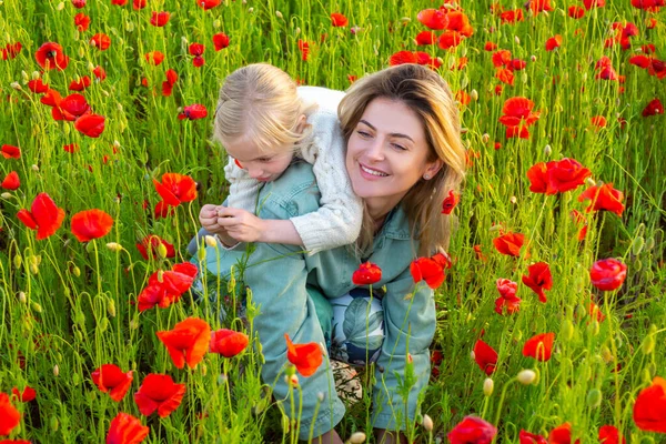 Mamá con una niña en un campo de amapolas rojas disfruta de la naturaleza. Madre e hija en el campo de amapola. Madre e hija en primavera. —  Fotos de Stock