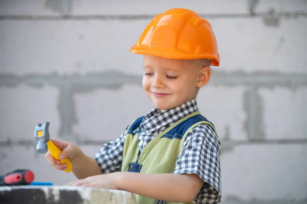 Портрет маленького строителя в касках с инструментами для ремонта на строительстве. Мальчик-строитель, плотник с набором инструментов для сборки. Ремонт дома. — стоковое фото