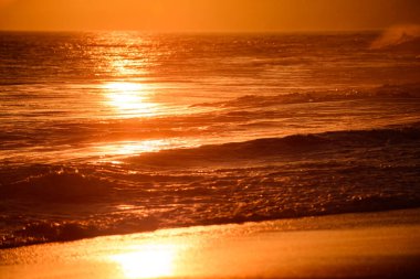 Altın gökyüzü ve okyanus suyu. Günbatımı ve okyanus ile soyut bir arkaplan. Deniz manzarasında gün batımı. Bulutlu dramatik günbatımı gökyüzü. Denizin üzerinde dramatik gün batımı.