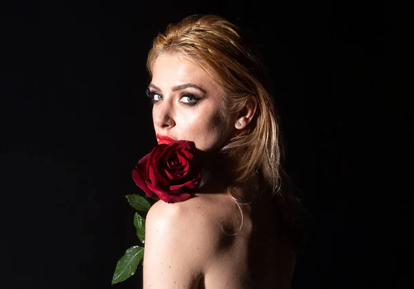 Bella donna viso e fiore. Ragazza e rosa rossa sul nero. Ritratto ravvicinato, cura della pelle, trucco. Concetto di cosmetica per profumi. Ritratto volto inalterato. Texture naturale della pelle. — Foto Stock