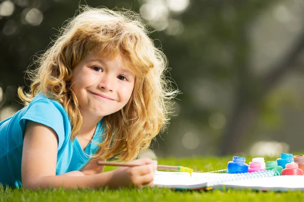 Счастливого талантливого художника-мальчика. Ребенок наслаждается искусством и рисованием на заднем дворе или в весеннем парке. Дети рисуют карандашами на открытом воздухе. — стоковое фото