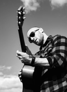 Doğada gitar çalan bir adam. Hipster adam yaz gününde dinleniyor..