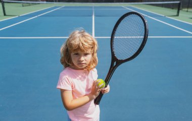 Tenis raketi ve topu dışarıda tenis kortunda olan bir çocuk. Çocuklar için spor egzersizi. Çocuklar için yaz etkinlikleri. Küçük çocuk için antrenman.