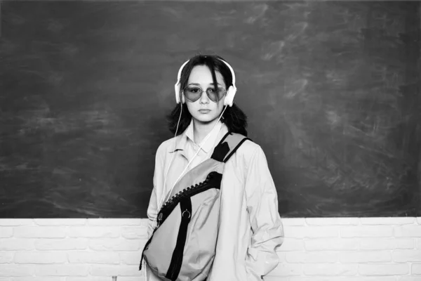 Joven adolescente colegiala con la mochila de la escuela y auriculares. Adolescente estudiante en pizarra. — Foto de Stock