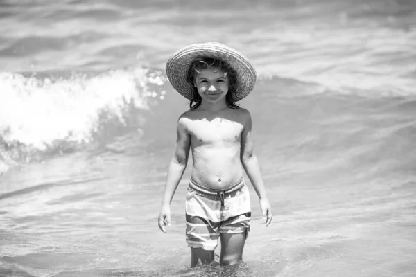 여름 방학 동안 해변에서 밀짚모자쓴 사랑 스런 소년. 바다 배경에서 장난기많은 아이의 모습. 재미있는 여름 소년의 얼굴. — 스톡 사진
