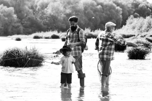 Tres generaciones de edad: abuelo, padre e hijo adolescente. El abuelo y el padre con el niño lindo están pescando. La pesca se convirtió en una actividad recreativa popular. — Foto de Stock