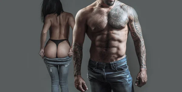 Jeans Shop. Getatoeëerd sexy man en vrouw. Succesvolle jonge knappe man met sexy meisjes. Jonge fashion mans benen in jeans. — Stockfoto