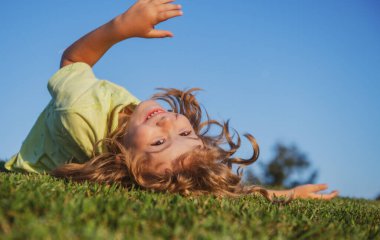 Yeşil çimlerde oynayan mutlu çocuk. Baharın bahçesinde komik bir çocuk. Çocuk günü. Mutlu tasasız çocukluk konsepti.