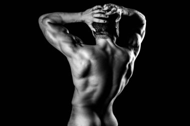 Siyah arka planda poz veren kaslı bir adamın arka planı. Vücut geliştirici ve striptiz teması. Çıplak gövde. Güçlü kıç..
