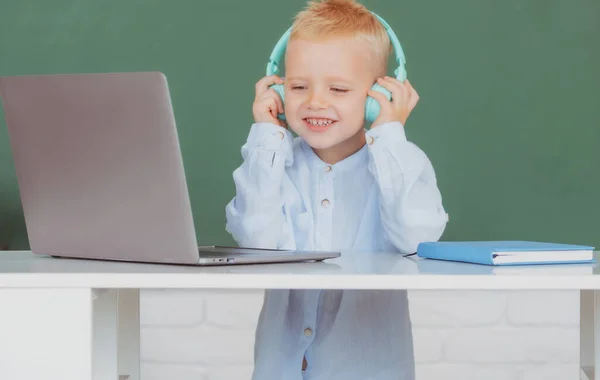 Enfant garçon dans les écouteurs à l'aide d'un ordinateur portable et étudier en ligne avec le professeur d'appel vidéo à l'école. Formation informatique. — Photo