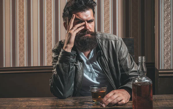 Mannen med skägg håller glaskonjak. En man som håller i ett glas whisky. Snygg snygg skäggig man dricker hemma efter jobbet. Fylld man. — Stockfoto