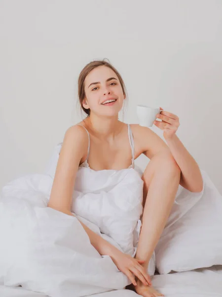 可怜的年轻女人在床上喝着一杯咖啡醒来。快乐的醒来，开始新的一天。休闲和休息。福利概念. — 图库照片