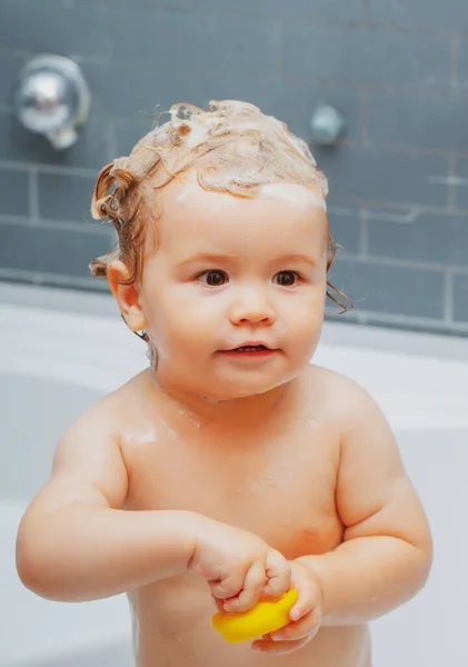 Cudowne dziecko bawiące się pianką. Dziecko kąpie się w wannie z pianką i bańkami mydlanymi. — Zdjęcie stockowe