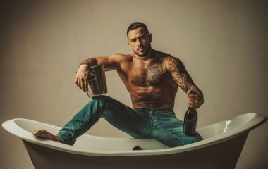 Kaslı adam banyoda küvette oturur, erkekler şampanyayla tatil yapar. Noel 'i ya da doğum gününü kutlamak için. Özel seks partisi.