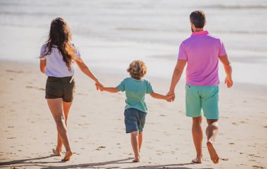 Kumsalda mutlu bir aile. İnsanlar yaz tatilinde eğleniyor. Baba, anne ve çocuk mavi denizde. Tasasız aile kavramı. Çocuklu aileler dışarıda rahatlar. Hafta sonu aile kavramı.