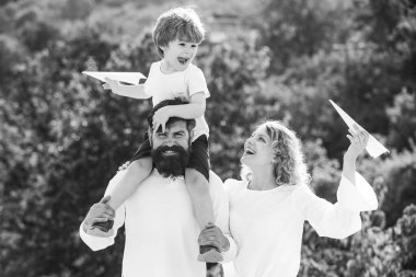 Sevimli küçük çocuk kağıt uçak tutuyor. Aile birlikte yaz saati gibi. Baba anne ve oğlu parkta. Yaz istihkakı. Ebeveyn -lik.