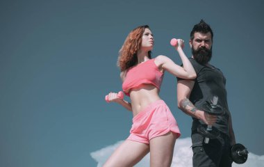 Güzel göbekli sakallı adam ve kadın. Dambıl kaldırma. Spor ve spor. Sportif çift açık havada antrenman yapıyor. Mükemmel vücut kası. Sağlıklı bir yaşam tarzı. Diyet yapıyorum. Özgürlük. Yaz etkinliği. halter ekipmanı