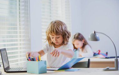 Okul çocuğu masada oturuyor, ödev yazıyor ya da sınava hazırlanıyor. Çocuk çalışmaya hazır. Biraz öğrenim.