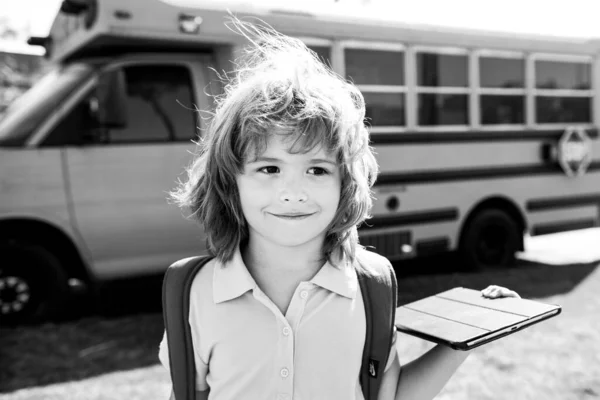 Schüler mit Tablet in der Nähe des Schulbusses. Soziale Distanz während der Quarantäne, Online-Bildungskonzept, Hausaufgabenbetreuung außerhalb. — Stockfoto