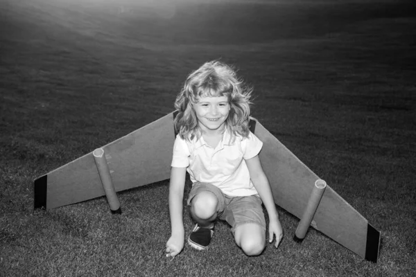Kind vliegen in vliegtuig gemaakt van kartonnen vleugels. Droom, verbeelding, gelukkige jeugd. — Stockfoto