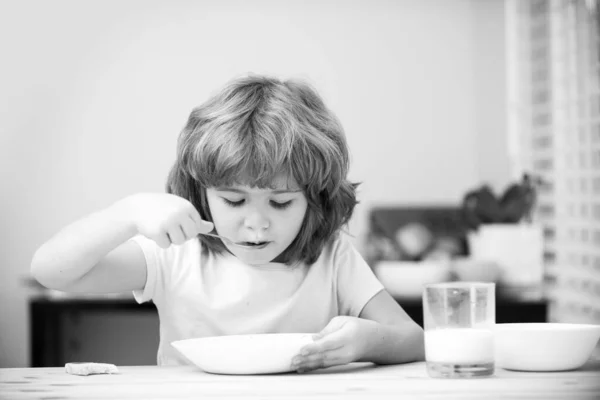 Portret van een kind dat soep eet of ontbijt terwijl hij thuis aan tafel luncht met een lepel. Kinderen gezond voedsel. — Stockfoto