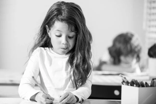 Веселий учень у класі в школі. Маленька дівчинка сидить за столом у класі. Портрет молодої школярки, яка вивчає і пише на ноутбуці. Концентровані маленькі школярі це весело, писати . — стокове фото