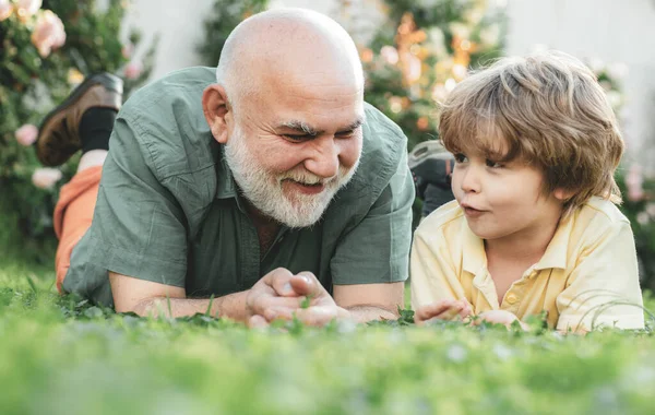 Avô e neto felizes relaxando juntos. Dia dos pais. Rapaz bonito com o pai a brincar ao ar livre. Duas gerações diferentes idades: avô e neto juntos. — Fotografia de Stock
