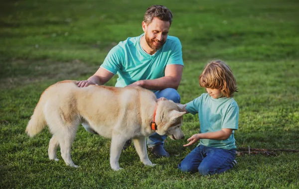 Lachende vader en zoon met huisdier. Gelukkig gezin met trouwe stamboom hond veel plezier in de achtertuin. — Stockfoto