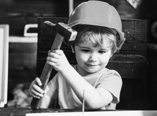 Le petit garçon avec un marteau fait des réparations. L'enfant participe activement à un processus artisanal. — Photo