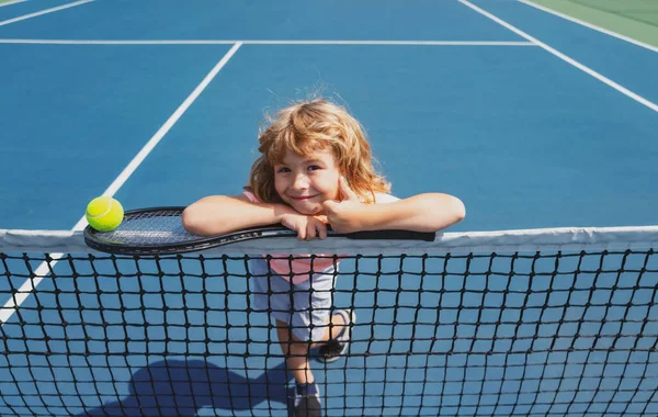 테니스 라켓을 입고 테니스장 야외에서 공을 던지는아이. 아이들을 위한 스포츠 운동. 어린이들을 위한 여름 활동. — 스톡 사진