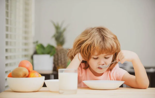 Portret van een kind dat soep eet of ontbijt terwijl hij thuis aan tafel luncht met een lepel. Kinderen gezond eten. Kindervoeding, voedingsconcept. — Stockfoto