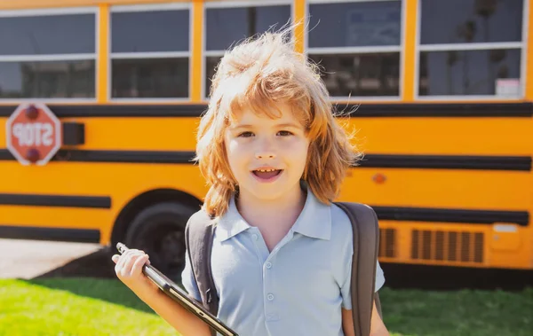 Умный школьник с цифровым планшетом в школьном парке возле школьного автобуса. Образование и обучение для детей. — стоковое фото