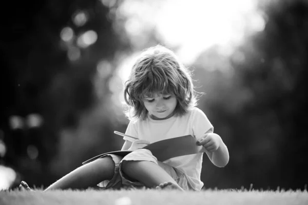 Niños a distancia aprendiendo. Alumno preescolar en el parque en la hierba. —  Fotos de Stock