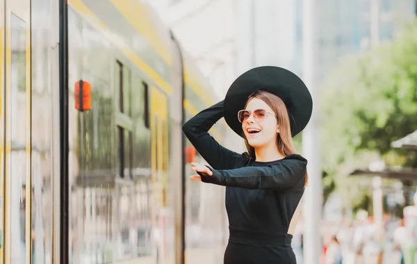 Женщина-модель бегает за автобусом-троллейбусом в летнем городе Европы. Модная женщина позирует на фоне улицы. Путешествие по городу. — стоковое фото