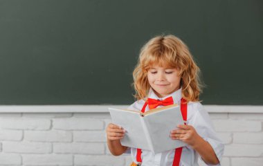 Okullu çocuk sınıfta bir kitap okuyor. Okuldaki sevimli çocuk. Çocuk sınıfta tahtayla ilgili bir şeyler öğreniyor. Okula dönüyorum, okuldaki ilk günüm..