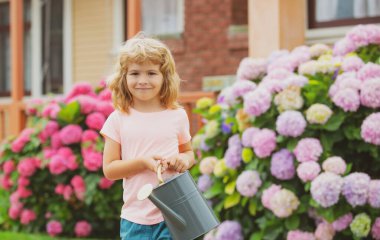 Çocuk, anne babaya su bidonuyla yardım ediyor. Bahçe malzemeleri.