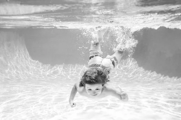 Glückliches Kind, das an einem Sommertag unter Wasser im Schwimmbad spielt. Kinder spielen im tropischen Resort. Familienurlaub am Strand. Kind schwimmt unter Wasser. — Stockfoto