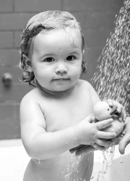 Schattige baby wassen in de badkamer. Een jongen met zeepcapsules op zijn haar die een bad neemt. Close-up portret van lachend kind, gezondheidszorg en kinderhygiëne. Kinderdouche. — Stockfoto