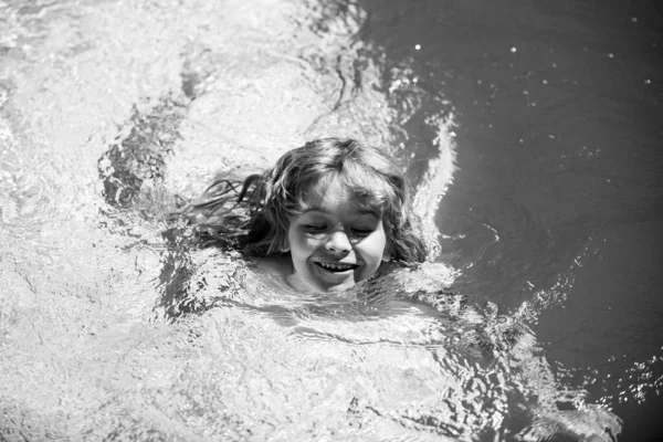 Мальчик плавает в воде бассейна. Ребенок играет на улице. Летний отдых и здоровый образ жизни. — стоковое фото