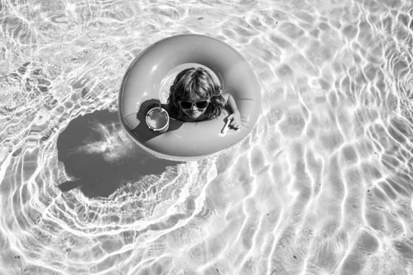 Summertime activities or adventure at aquapark. Summer kids weekend or vacation. Funny happy child boy in swiming pool on inflatable rubber circle ring. — Stock Photo, Image