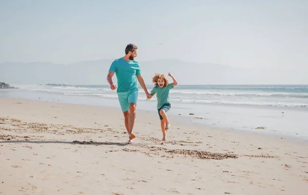 Pai e filho correndo na praia de verão. Pai e criança brincando ao ar livre. Conceito de família feliz. — Fotografia de Stock