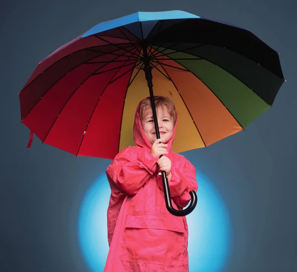 Niedlichen kleinen Jungen bereiten sich auf den Herbst vor. Kinder haben Spaß mit dem Laubfall. Wolken regen Regenschirm. Regenkonzept. fröhlicher Junge im Regenmantel mit buntem Regenschirm. Regenende Kinder. — Stockfoto