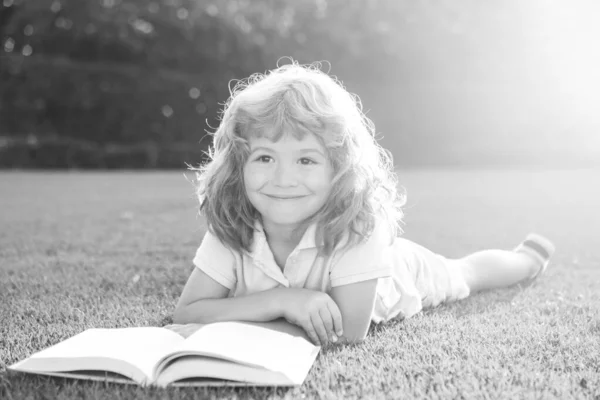 Slimme kinderen. Leuke jongen die een boek op gras leest. Kind leest een boek in het zomerpark. — Stockfoto