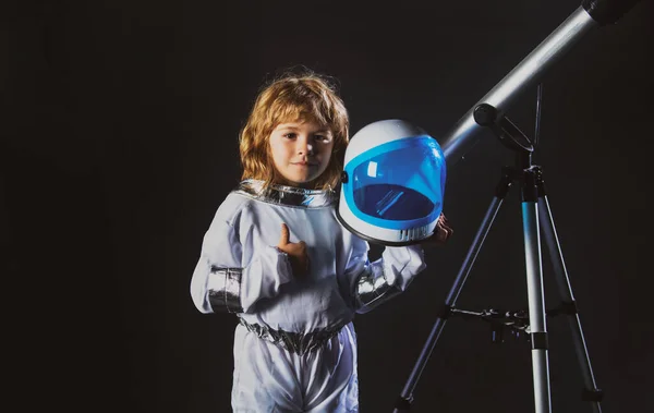 El niño con un telescopio está vestido con un traje de astronauta. Concepto de astronomía y astrología. — Foto de Stock
