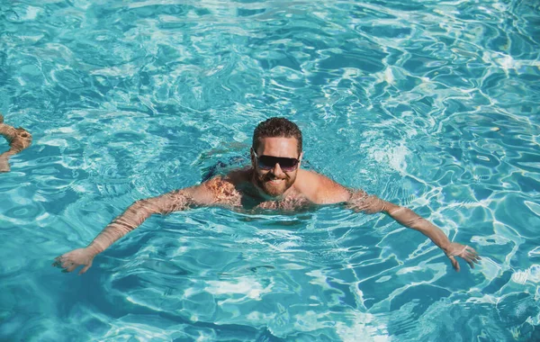Station balnéaire estivale. Homme en vacances d'été. Guy aux lunettes de soleil relaxant dans la piscine. — Photo