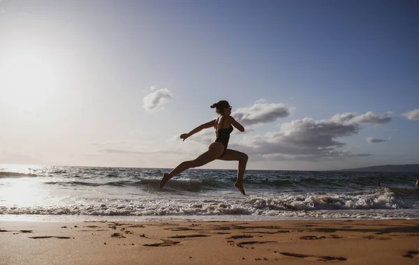 海岸を走っている女性。健康的な女性は海で実行します,女の子はスポーツ屋外を行う,幸せな女性の運動,自然背景上のフィットネスやヘルスケアの概念. — ストック写真